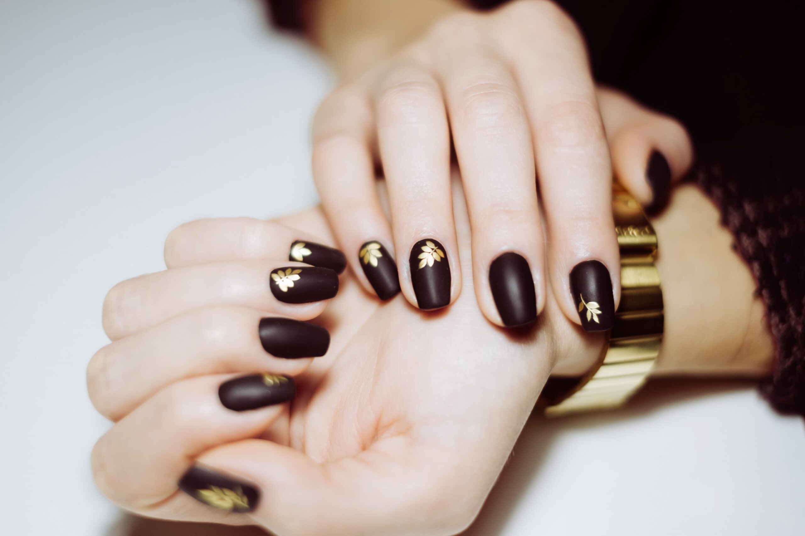 elegant-black-matte-manicure-with-golden-leaf-accents-showcased-wellgroomed-hands-stylish-setting-min-min